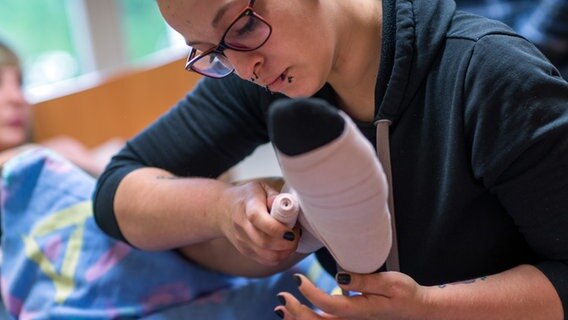 Eine Pflegeschülerin legt bei einer Mitschülerin einen Thrombose-Verband an. © dpa Foto: Jens Büttner