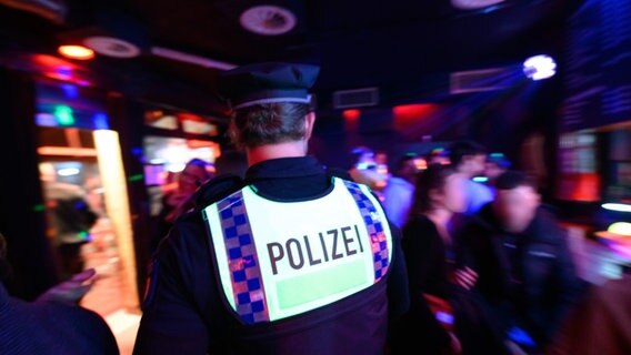 Ein Polizist läuft bei einer Kontrolle durch ein Lokal nahe der Reeperbahn im Hamburger Stadtteil St. Pauli. © picture alliance / dpa Foto: Jonas Walzberg