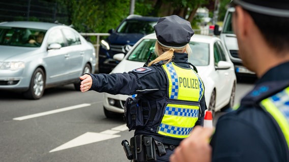 Eine Polizistin weist Autos nahe dem Volksparkstadion den Weg. (Archivfoto) © Jonas Walzberg/dpa 