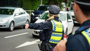 Eine Polizistin weist Autos nahe dem Volksparkstadion den Weg. (Archivfoto) © Jonas Walzberg/dpa 
