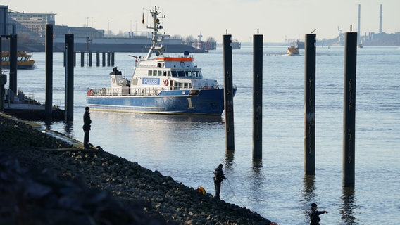 Polizeitaucher und Polizeibeamte suchen in der Elbe nach einem vermissten Jungen. Im Hintergrund ist ein Polizeiboot zu sehen. © picture alliance / dpa 