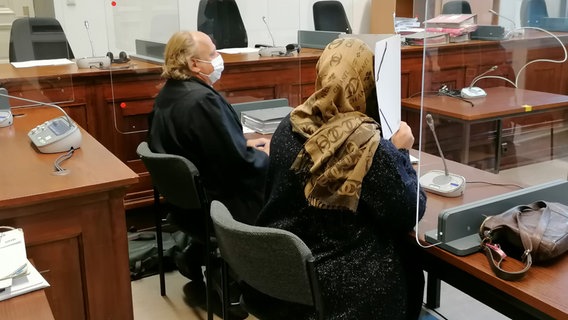 Die Angeklagte sitzt im Gerichtssaal und verdekt ihr Gesicht mit einem Aktenordner. © NDR Foto: Elke Spanner