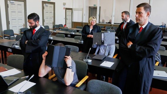 Zwei Angeklagte sitzen umringt von ihren Verteidigern vor Prozessbeginn im Gerichtssaal des Hamburger Landgerichts. © Georg Wendt/dpa Foto: Georg Wendt