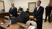 Ein Angeklagter versteckt sich im Gerichtssaal des Hamburger Strafjustizgebäudes unter einer Jacke. © NDR Foto: Elke Spanner