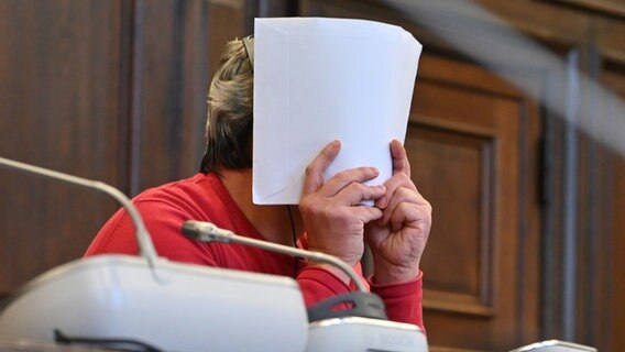 Ein 47 Jahre alter Angeklagter verdeckt sein Gesicht im Saal des Hamburger Landgerichts. Er soll einen 62 Jahre alten Mann erstochen haben. © picture alliance/dpa Foto: Jonas Walzberg