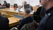 Ein Angeklagter sitzt vor Prozessbeginn in einem Gerichtssaal in Hamburg. Er soll auf der Reeperbahn einer Transfrau mit der Faust ins Gesicht geschlagen haben. © picture alliance / dpa Foto: Daniel Reinhardt