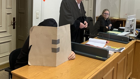 Ein Angeklagter verdeckt in einem Saal des Hamburger Landgerichts sein Gesicht. Er soll soll auf St. Pauli mehreren Schülerinnen aus Bayern zwangsweise Wodka eingeflößt und die Schulklasse bestohlen haben © NDR Foto: Elke Spanner