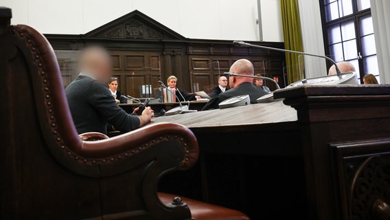 Ein Angeklagter (links) sitzt zu Beginn des Prozesstages mit seinen Anwälten im Gerichtssaal des Hamburger Landgerichts. © dpa Foto: Christian Charisius