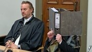 Eine Angeklagte sitzt in Hamburg in einem Gerichtssaal neben ihrem Verteidiger und verdeckt ihr Gesicht. © NDR Foto: Elke Spanner