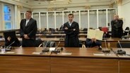 Drei Frauen sind in Hamburg wegen Menschenhandels angeklagt. Sie sitzen im Gerichtssaal und verdecken ihr Gesicht, neben ihnen stehen ihre Anwälte. © NDR Foto: Elke Spanner