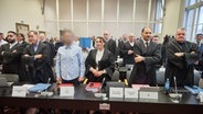 Angeklagte und ihre Anwälte stehen im Gerichtssaal vor Beginn des Prozess gegen eine mutmaßliche Diebesbande, die insgesamt zwölf Straftaten zum Nachteil des Unternehmens Aurubis verübt haben soll. © Georg Wendt/dpa Foto: Georg Wendt