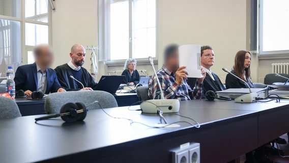 Die Angeklagten in einem Prozess wegen schweren Menschenhandels am Landgericht Hamburg sitzen neben ihren Anwälten. © Christian Charisius/dpa 