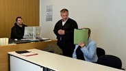 In Hamburg muss sich eine Pflegerin wegen Körperverletzung vor Gericht verantworten. Sie hält sich einen grünen Ordner vor ihr Gesicht. © NDR Foto: Elke Spanner