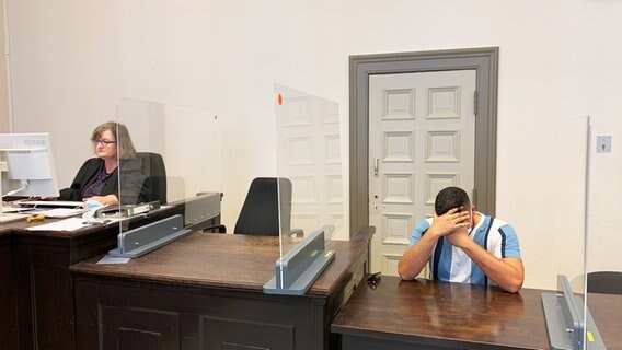 Ein Angeklagter sitzt auf der Anklagebank und hält sich die Hände vors Gesicht © NDR / Elke Spanner Foto: Elke Spanner