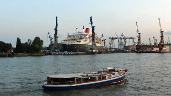 Die "Queen Mary 2" im Dock Elbe 17 von Blohm + Voss. Im Vordergrund fährt die Party Barkasse "Frau Hedi" © NDR Foto: Heiko Block