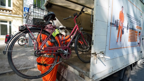 Ein Mitarbeiter der Stadtreinigung Hamburg stellt ein Schrottfahrrad auf die Ladefläche eines Fahrzeugs. © picture alliance / dpa Foto: Marcus Brandt