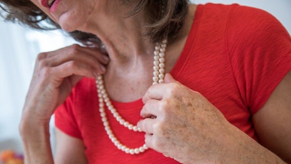Eine Frau rückt ihre Perlenkette zurecht. (Symbolfoto)  Foto: picture alliance / dpa Themendienst | Christin Klose