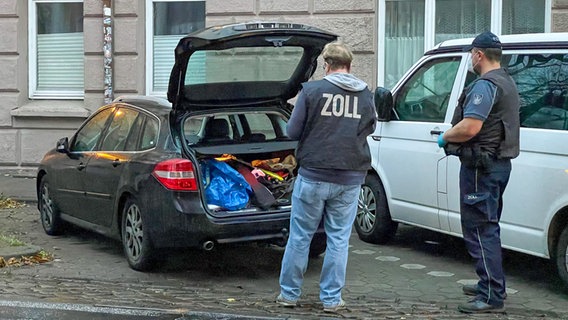 Zollbeamte stehen während einer Razzia im Hamburger Stadtteil Wilhelmsburg vor einem Fahrzeug mit geöffneten Kofferraum.  