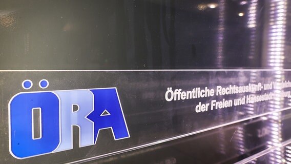 Das Logo der ÖRA (Öffentliche Rechtsauskunft und Vergleichsstelle der Freien und Hansestadt Hamburg) ist am Eingang zu dem Bürogebäude in der Innenstadt zu sehen. © picture alliance/dpa Foto: Christian Charisius