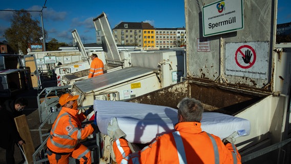 Mitarbeiter der Hamburg Stadtreinigung werfen eine Matratze in einen Sperrmüllcontainer auf dem Recyclinghof in St. Pauli © picture alliance / dpa Foto: Christian Charisius