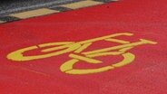 Ein gelbes Fahrrad-Symbol ist auf rotem Straßenbelag auf der Reeperbahn aufgebracht. © picture alliance / dpa Foto: Kilian Genius
