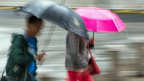 Menschen gehen mit aufgespannten Regenschirmen durch die Hamburger Innenstadt. © picture alliance / dpa Foto: Lukas Schulze