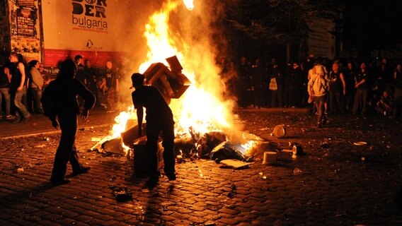 Randalierer werfen am Samstag (20.08.2011) Müll in ein Feuer vor dem alternativen Kulturzentrum "Rote Flora" im Schanzenviertel in Hamburg während der Ausschreitungen nach dem Schanzenfest. © dpa Foto: Angelika Warmuth