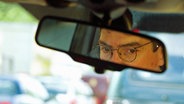 Ein Mann schaut in den Rückspiegel seines Autos. © picture-alliance Foto: Engelsmann Gerd