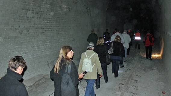 Besucher gehen mit Taschenlampen durch den Schellfischtunnel. © NDR Foto: Daniel Sprenger