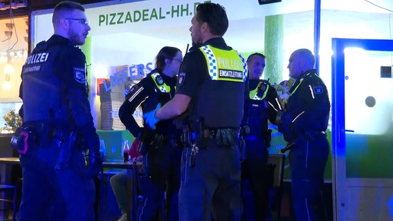 Mehrere Polizisten stehen vor einer Pizzeria. © TNN 