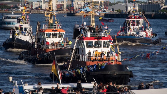 Besucher des Hamburger Hafengeburtstags betrachten die Schlepper beim traditionellen Schlepperballett, bei dem die Schiffe zur Walzermusik "tanzen". © picture alliance / dpa Foto: Axel Heimken