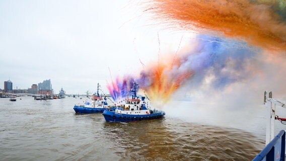 Bunte Pyrotechnik wird zum Ende des Schlepperballetts beim 834. Hafengeburtstag an Bord der Schlepper auf der Elbe gezündet. © Jonas Walzberg/dpa 