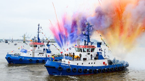 Bunte Pyrotechnik wird zum Ende des Schlepperballetts beim 834. Hafengeburtstag an Bord der Schlepper auf der Elbe gezündet. © picture alliance/dpa | Jonas Walzberg 