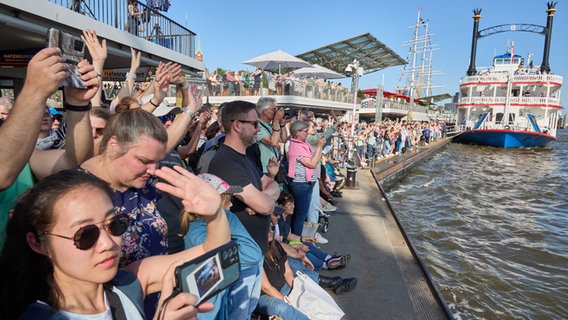 Zahlreiche Zuschauer stehen während des 835. Hamburger Hafengeburtstages auf der Pontonanlage an den Landungsbrücken um das Schlepperballett zu sehen. © picture alliance/dpa Foto: Georg Wendt