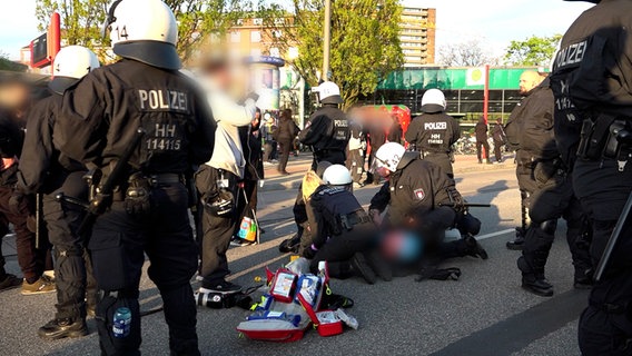 Polizistinnen und Polizisten kümmern sich gemeinsam mit Sanitätern um einen Verletzten. Er war bei einem Polizeieinsatz während einer Mai-Demo am Hamburger U-Bahnhof Schlump gestürzt. © HamburgNews Foto: HamburgNews