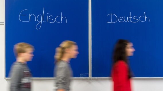 Schüler gehen in einem Klassenzimmer vor einer Tafel mit der Aufschrift "Englisch - Deutsch". © picture alliance / dpa Foto: Armin Weigel