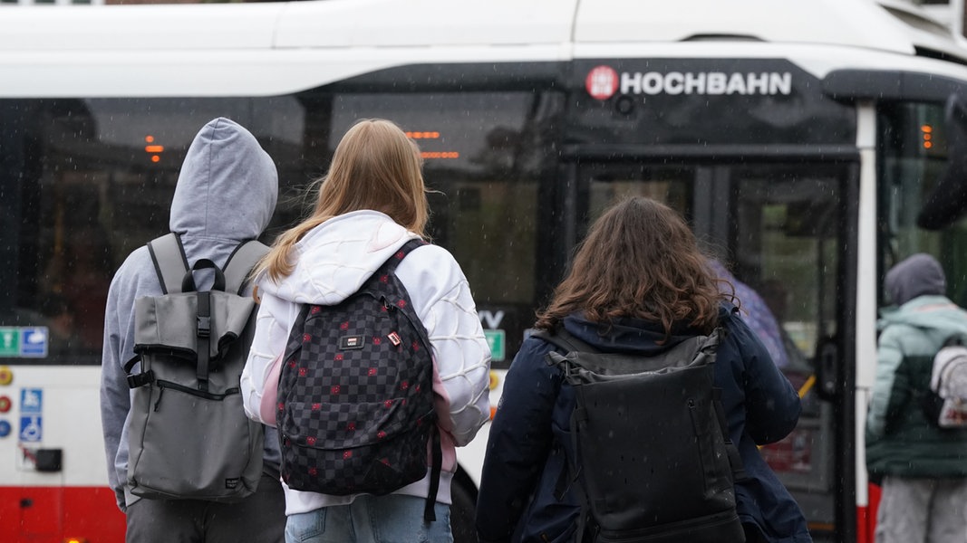 Schülerinnen und Schüler vor einem Bus der Hamburger Hochbahn. 