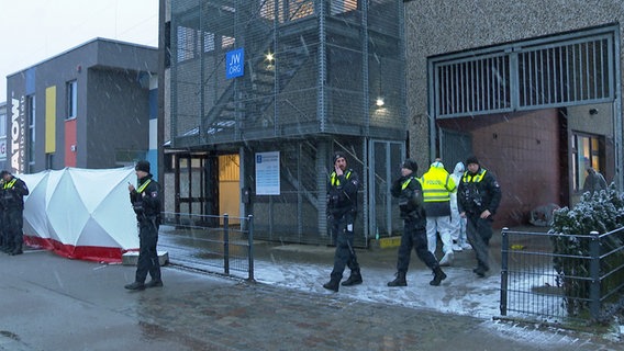 Polizisten stehen am 10. März 2023 vor einem Gebäude der Zeugen Jehovas in Hamburg. Dort waren mehrere Menschen getötet und einige Personen verletzt worden. © picture alliance/dpa/Tnn Foto: Steven Hutchings
