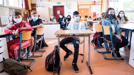 Schüler einer 7. Klasse der Max-Schmeling-Stadtteilschule sitzen zu Beginn des Unterrichts mit Mund-Nasen-Bedeckungen im Klassenraum. © picture alliance/Daniel Bockwoldt/dpa Foto: Daniel Bockwoldt