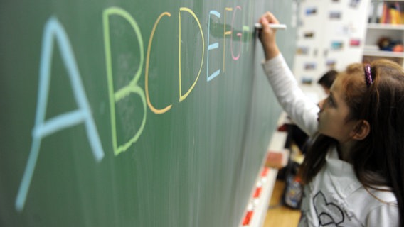 Ein Mädchen mal Buchstaben auf eine Tafel © picture alliance / dpa Foto: Daniel Reinhardt