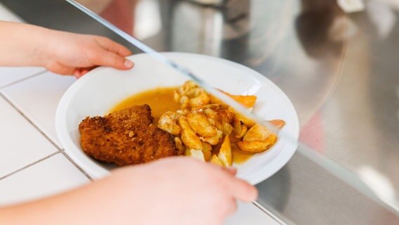 Eine Grundschülerin nimmt einen Teller mit Schnitzel, Kartoffeln und Soße vom Tresen der Essensausgabe einer Schulmensa. © picture alliance/dpa Foto: Philipp von Ditfurth