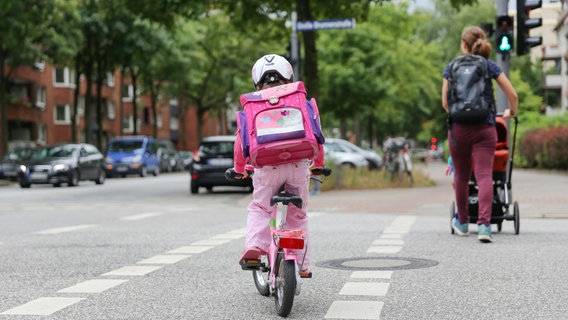 Ein kleines Mädchen fährt mit einem Fahrrad über eine Strasse. © picture alliance/dpa Foto: Mascha Brichta