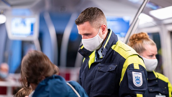 Mitarbeiter der Hamburger Hochbahn-Wache kontrollieren die Einhaltung der Maskenpflicht in einer U-Bahn. © picture alliance/dpa Foto: Daniel Reinhardt