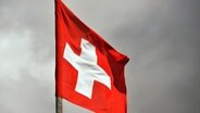 Eine Schweizer Flagge weht vor dunklen Wolken im Wind. © picture alliance/Thomas Muncke Foto: Thomas Muncke