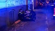 Ein verletzter Polizist wird von einer Kollegin behandelt. © NonstopNews 