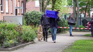Zwei Polizisten stellen Beweismittel aus einem Wohngebäude in Hamburg sicher. © tv7news.de 