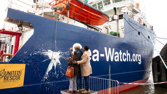 Das Rettungsschiff "Sea-Watch 5" wird von den Geflüchteten und Mitgliedern von Flüchtlingshilfsorganisationen mit einer am Schiff zerschellenden Sektflasche getauft. © dpa Foto: Daniel Bockwoldt