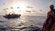 Die von der Seenotrettungsorganisation Sea-Eye herausgegebene Aufnahme zeigt Seenotretter vom Rettungsschiff "Alan Kurdi" die zu einem Schlauchboot voller Flüchtlinge schauen.  Foto: Pavel D. Vitko