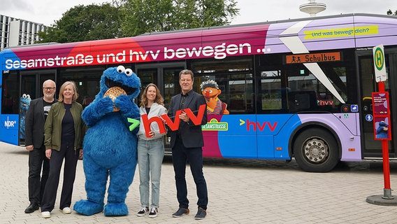 Ole Kampovski (NDR), Kerstin Hintze (Sesame Workshop Europe), Raimund Brodehl und Melanie Ruhl (HVV) präsentieren gemeinsam mit Krümelmonster den neuen "Sesamstraße"-Bus. © NDR/hvv/obs 