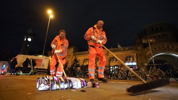 Mitarbeiter der Hamburger Stadtreinigung räumen an den Landungsbrücken Flaschen und abgebrannte Feuerwerkskörper von den Straßen und Gehwegen. © picture alliance / dpa Foto: Marcus Brandt